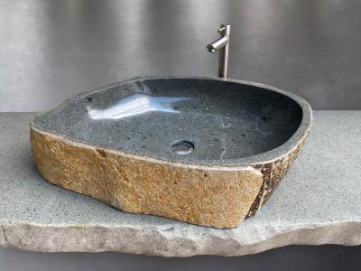 Lavabo de piedra natural de forma irregular con acabado rústico.