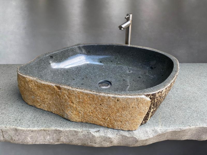 Lavabo de piedra natural de forma irregular con acabado rústico.